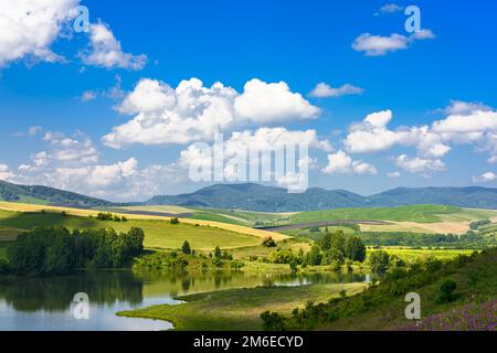 Paesaggio con colline e lago in una giornata di sole Foto Stock