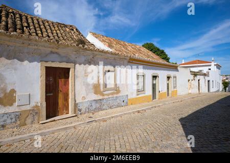 Una visione di tipico, generico, vecchio, povero, umile, Semplice casa moresca, architettura domestica con pareti in stucco peeling, tetti in tegole arancioni spagnole. A Tavira Foto Stock