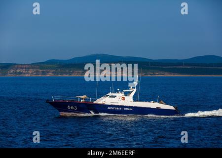 Una barca della Guardia Costiera va ad alta velocità attraverso l'area acquatica di Vladivostok Foto Stock