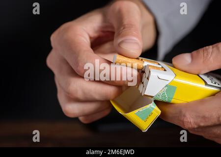 Sigaretta. Mondo No concetto di giornata del tabacco. Primo piano mano uomo che tiene pelare fuori pacchetto di sigarette preparare fumare una sigaretta Foto Stock