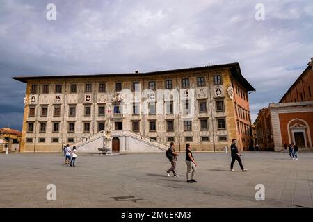 Pisa, Italia - turisti che camminano davanti al Palazzo della Carovana in Piazza dei Cavalieri Foto Stock