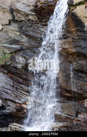 Getti d'acqua che cadono dalla cascata di Lillaz (Cascate di Lillaz) sulle formazioni geologiche carsiche alpine. Cogne, Valle d'Aosta, Italia (foto verticale ) Foto Stock