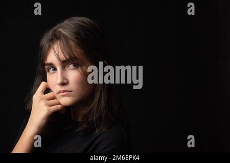 Ritratto d'arte di sedici anni ragazza adolescente al buio vestiti su sfondo nero Foto Stock