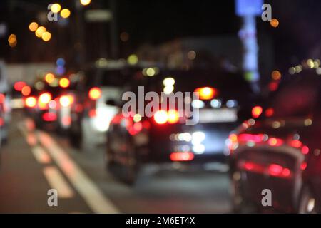 Automobili con fari e luci accese nella città di notte. Vetture con fari accesi. Ingorgo di traffico alla vigilia Foto Stock