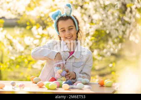 Felice ragazza teen indossare coniglietto orecchie con le uova di Pasqua in giardino Foto Stock