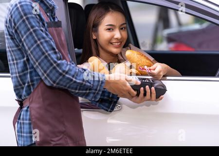 Donna asiatica che fa il pagamento contactless per la drogheria Foto Stock