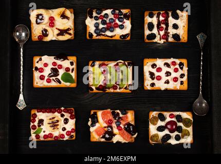 Belle torte quadrate con una varietà di ripieni di frutti di bosco. Un dolce bellissimo dessert. Assortimento di pezzi di torta Foto Stock