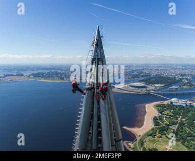 Gli installatori di lavoratori all'altezza lavorano alla parte superiore del grattacielo. Foto Stock