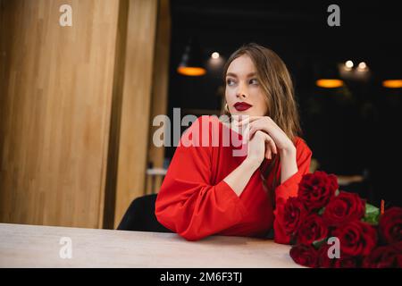 giovane donna sognante guardando via vicino rose rosse il giorno di san valentino, immagine stock Foto Stock