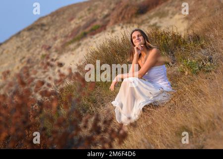 Una ragazza in un vestito bianco gode di una bella vista del tramonto Foto Stock