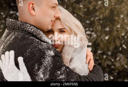 Una coppia affettuosa in un dolce abbraccio. Il ragazzo bacia la sua ragazza. San Valentino. Giovane ragazzo abbraccia la sua ragazza nel parco d'inverno. Foto Stock