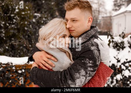 Una coppia affettuosa in un dolce abbraccio. Il ragazzo bacia la sua ragazza. San Valentino. Giovane ragazzo abbraccia la sua ragazza nel parco d'inverno. Foto Stock