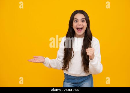 I punti positivi del bambino dell'adolescente a parte con l'espressione allegra, mostra stupefacente allo spazio vuoto vuoto. Pubblicità e mockup. Ragazza giovane eccitata. Foto Stock