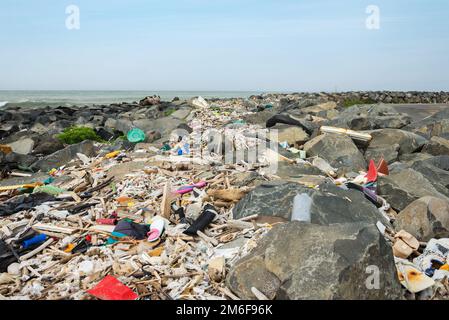 Spazzatura rovesciato sulla spiaggia vicino alla grande città. Svuotare le bottiglie di plastica sporche usate e altri rifiuti. Inquinamento ambientale. Eco Foto Stock