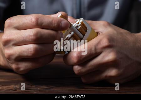 primo piano mano uomo che tiene la buccia dal pacchetto di sigarette preparare fumare una sigaretta. Linea di imballaggio in alto. Foto Stock