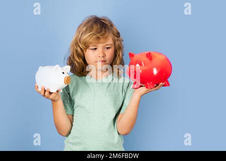 Piggy Bank per soldi. Capretto che mette la moneta nella banca del piggy per il risparmio con il mucchio delle monete. Piggybank con monete e concetto di bambino. Foto Stock