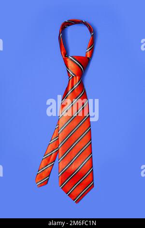 Cravatta a righe rossa da uomo staccata per il tempo libero, isolata su sfondo blu. Foto Stock
