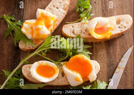 Uova sode rotte su baguette Foto Stock