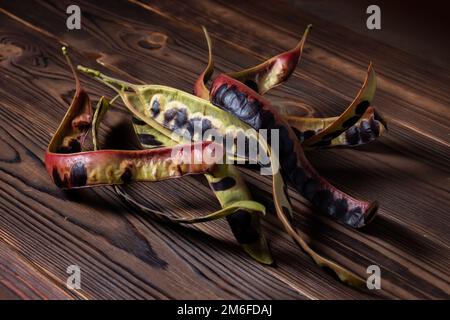 Semi di acacia su sfondo di legno. Primo piano. Foto Stock