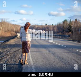 La ragazza ferma la macchina in autostrada con la mano. Foto Stock