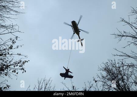 Servizio di emergenza paramedico con paziente sospeso con corda sotto elicottero. Salvataggio da terreni difficili da raggiungere. Foto Stock