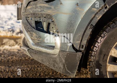 La parte anteriore della crossover grigia viene danneggiata da un incidente stradale. Riparazione di automobile o concetto di assicurazione di automobile. Danni e graffi al parafango anteriore e alla luce Foto Stock