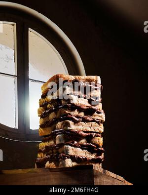 Grande sandwich di crema al cioccolato composto da diversi pezzi di pane tostato contro una finestra Foto Stock