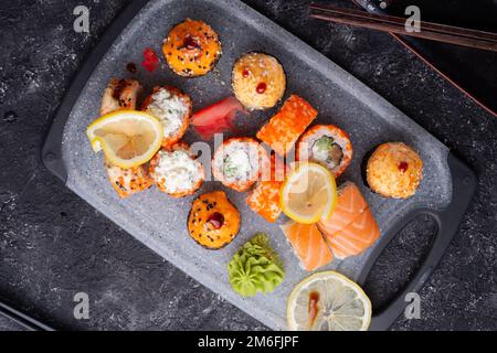 Set di sushi serviti al vassoio grigio al tavolo nero. giacitura piatta. Foto Stock