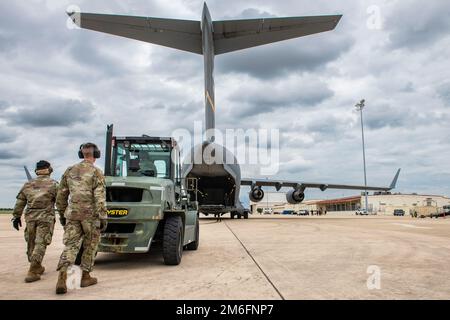 Airman del 97th Logistics Readiness Squadron si prepara a scaricare il carico da un C-17 Globemaster III presso Joint base San Antonio-Kelly Field, Texas, 27 aprile 2022. La 97th Air Mobility Wing ha implementato C-17, personale di supporto e equipaggio della base dell'aeronautica militare Altus, Okla. A Kelly Field, come parte della Task Force Red Mammoth, che garantisce che l'unità possa fornire una portata globale per le operazioni di combattimento e di emergenza, continuando al contempo la formazione in un ambiente mobile. Foto Stock