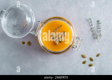 Zuppa di purea di zucca con semi di zucca e timo in un vaso di vetro. Vista dall'alto. Foto Stock