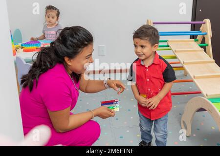 Medico pediatrico ridendo con un bambino, nell'area giochi del suo ufficio medico. Foto Stock