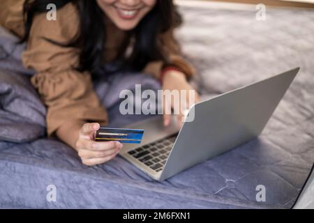 Donna asiatica che utilizza la carta di credito shopping online con computer portatile durante le vacanze in viaggio Foto Stock