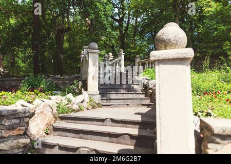 Una vecchia scala con colonne in pietra e ringhiere nel parco cittadino Foto Stock