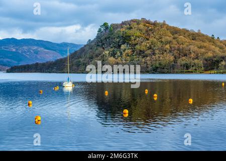 Yacht ormeggiato a Bandry Bay, che separa la piccola isola boscosa di Inchtavannach da Aldochlay, sulla sponda occidentale di Loch Lomond in Scozia, Regno Unito Foto Stock