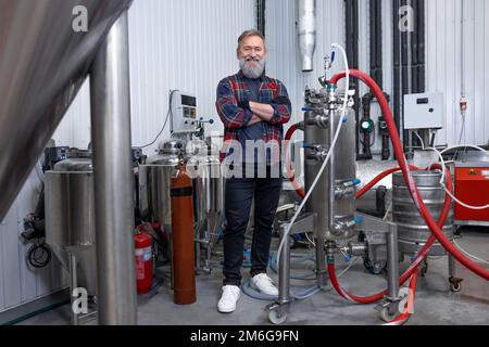 Uomo in camicia a quadri che lavora al birrificio e che guarda soddisfatto Foto Stock