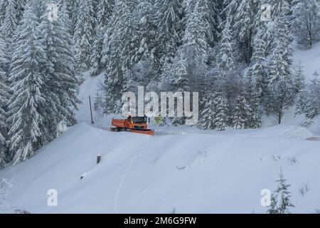 Spazzaneve autocarro pulendo strada nevosa in tempesta di neve. Nevicate sul vialetto. Foto Stock