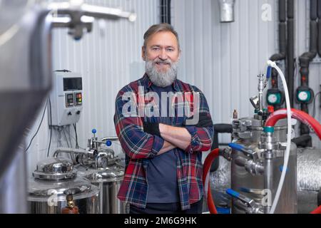 Uomo in camicia a quadri che lavora al birrificio e che guarda soddisfatto Foto Stock