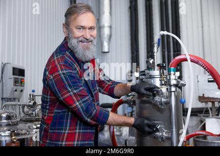 Uomo in camicia a quadri che lavora al birrificio e che guarda soddisfatto Foto Stock