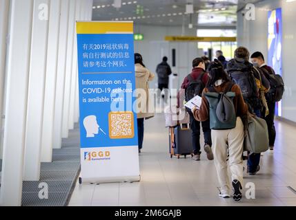 SCHIPHOL - Paesi Bassi, 04/01/2023, SCHIPHOL - i viaggiatori provenienti dalla Cina passano davanti a un banner con informazioni e ricevono un test automatico corona gratuito all'arrivo a Schiphol. Gli autotest vengono forniti con informazioni su come utilizzarli in mandarino o cantonese. ANP ROBIN VAN LONKHUIJSEN olanda fuori - belgio fuori Foto Stock