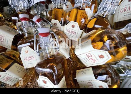 Bottiglie di grappa in un cesto in un mercato a riva del garda Foto Stock