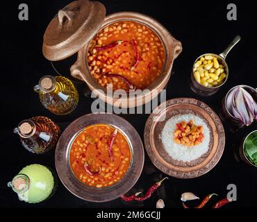 Cibo turco sul tavolo fagiolo al forno pilaf (fagioli blu scuro e riso). Cucina tradizionale locale con vista dall'alto. Alimenti turchi; fagiolo essiccato (kuru Foto Stock