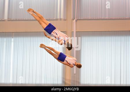 Due ragazzi si allenano in salto sincronizzato su un trampolino Foto Stock