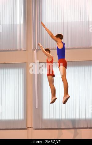 Due ragazzi si allenano in salto sincronizzato su un trampolino Foto Stock