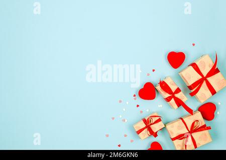 Molti cuori e scatole di regali in carta da imballaggio legato nastro rosso su sfondo blu. Concetto di St. San Valentino, matrimoni, impegni, Madre Foto Stock
