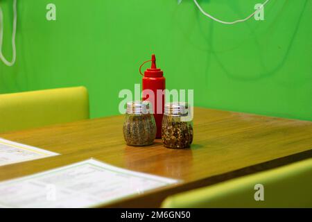 Tavoli e sedie sono disposti in un buon negozio di cibo interno fresco e luminoso con un tema di colore scuro. Foto Stock