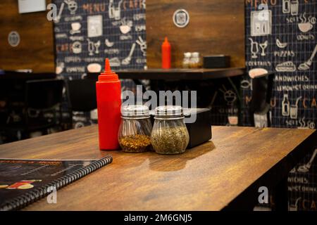 Tavoli e sedie sono disposti in un buon negozio di cibo interno fresco e luminoso con un tema di colore scuro. Foto Stock