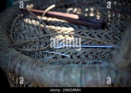 Abile artigiano che lavora manualmente una dettagliata poltrona in legno di bambù con le dita e gli utensili Foto Stock