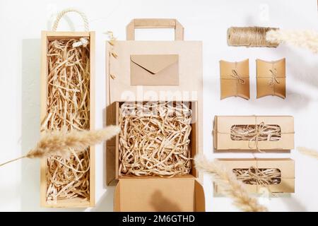 Concetto di imballaggio ecologico. Set di scatole di cartone con carta grattugiata all'interno, sacchetto di carta e piccole scatole regalo per il confezionamento di articoli da stor online Foto Stock