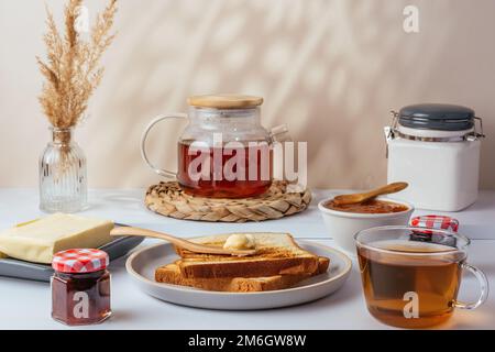 tostare con burro su un piatto e il tè in una tazza Foto Stock