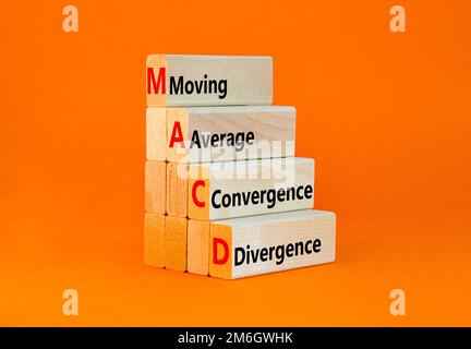 Simbolo MACD. Concetto parole MACD movimento media convergenza divergenza su blocco di legno su bellissimo sfondo arancione. Business MACD Moving Average con Foto Stock